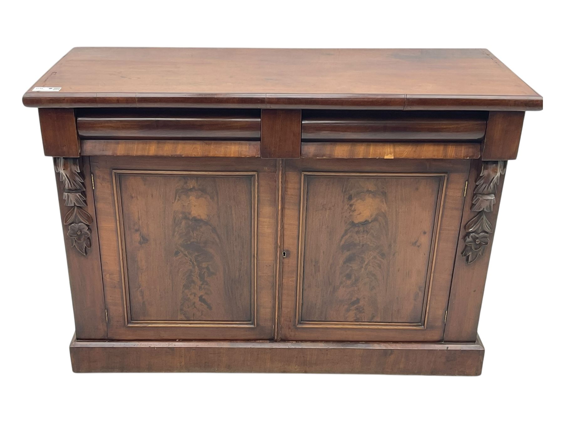 Mid 19th century mahogany sideboard, rectangular top over two frieze drawers with rounded edges, flanked by floral carved corbels, over two panelled cupboard doors, raised on a plinth base