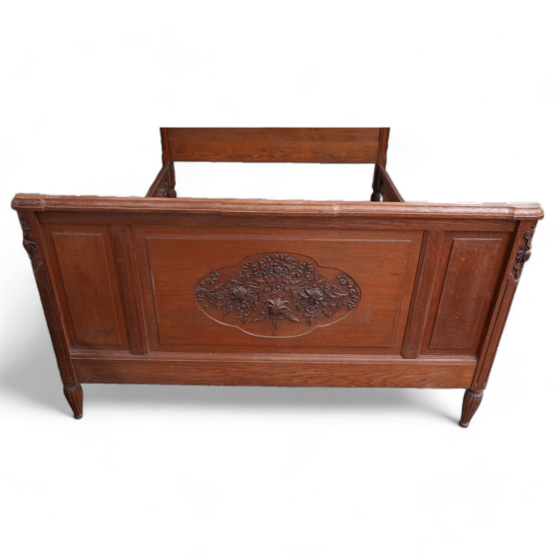 Late 19th century French oak double bedstead, headboard with shaped rail and carved pediment, carved footboard