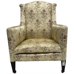 Edwardian hardwood-framed armchair, upholstered in floral pattern fabric, on square tapering front supports, brass and ceramic castors 