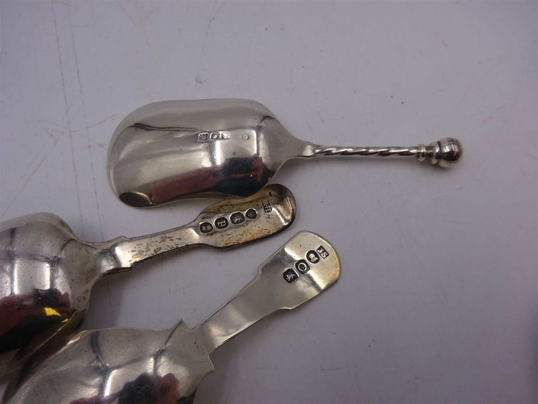 Three silver caddy spoons, comprising George III Fiddle pattern example, William IV Fiddle pattern example with later engraved bowl. and shovel example with twist handle, hallmarked some elements indistinct