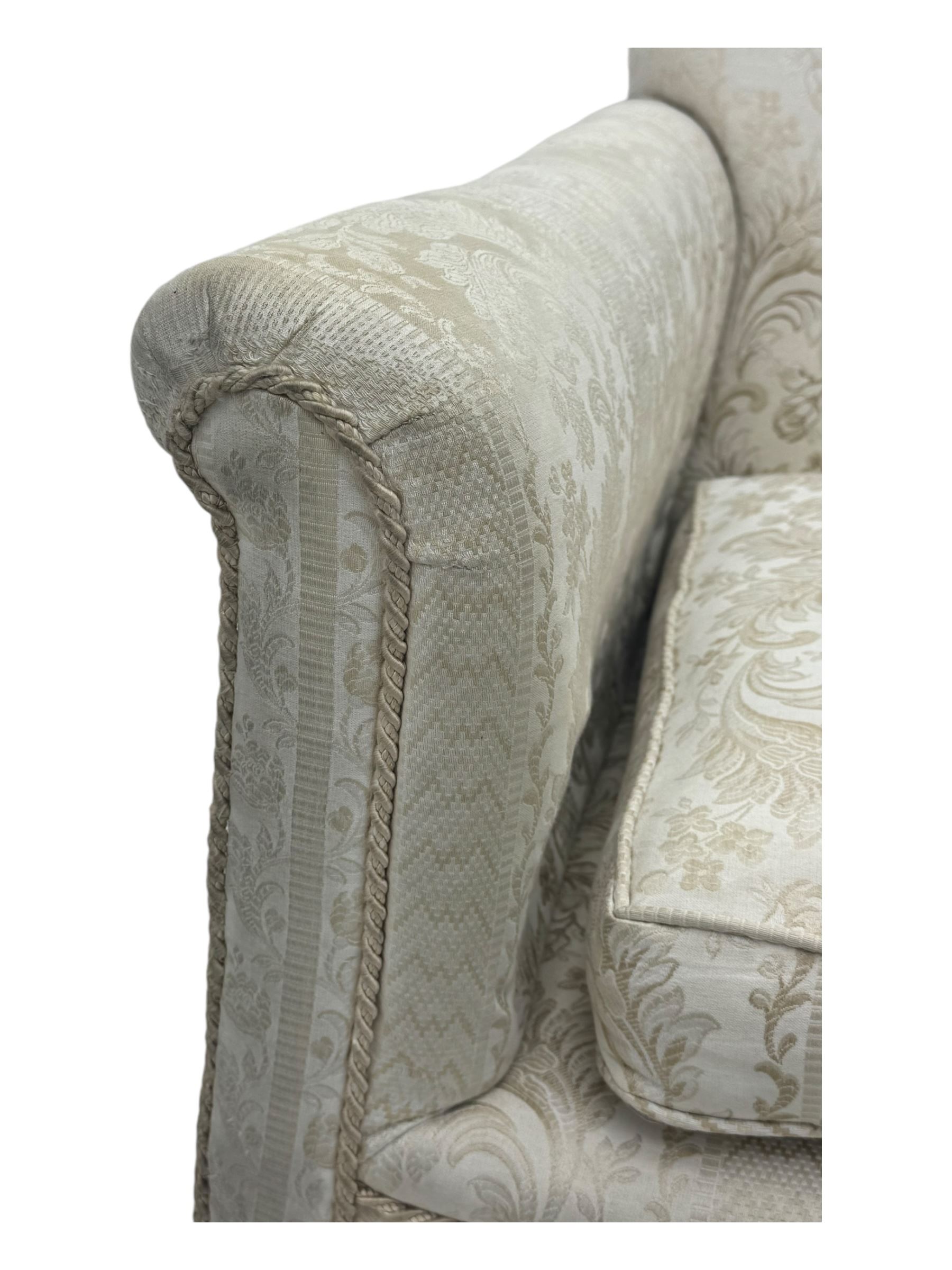 Early 20th century mahogany framed two-seat sofa, upholstered in pale fabric decorated with scrolling foliage, on acanthus carved ball and claw cabriole feet 