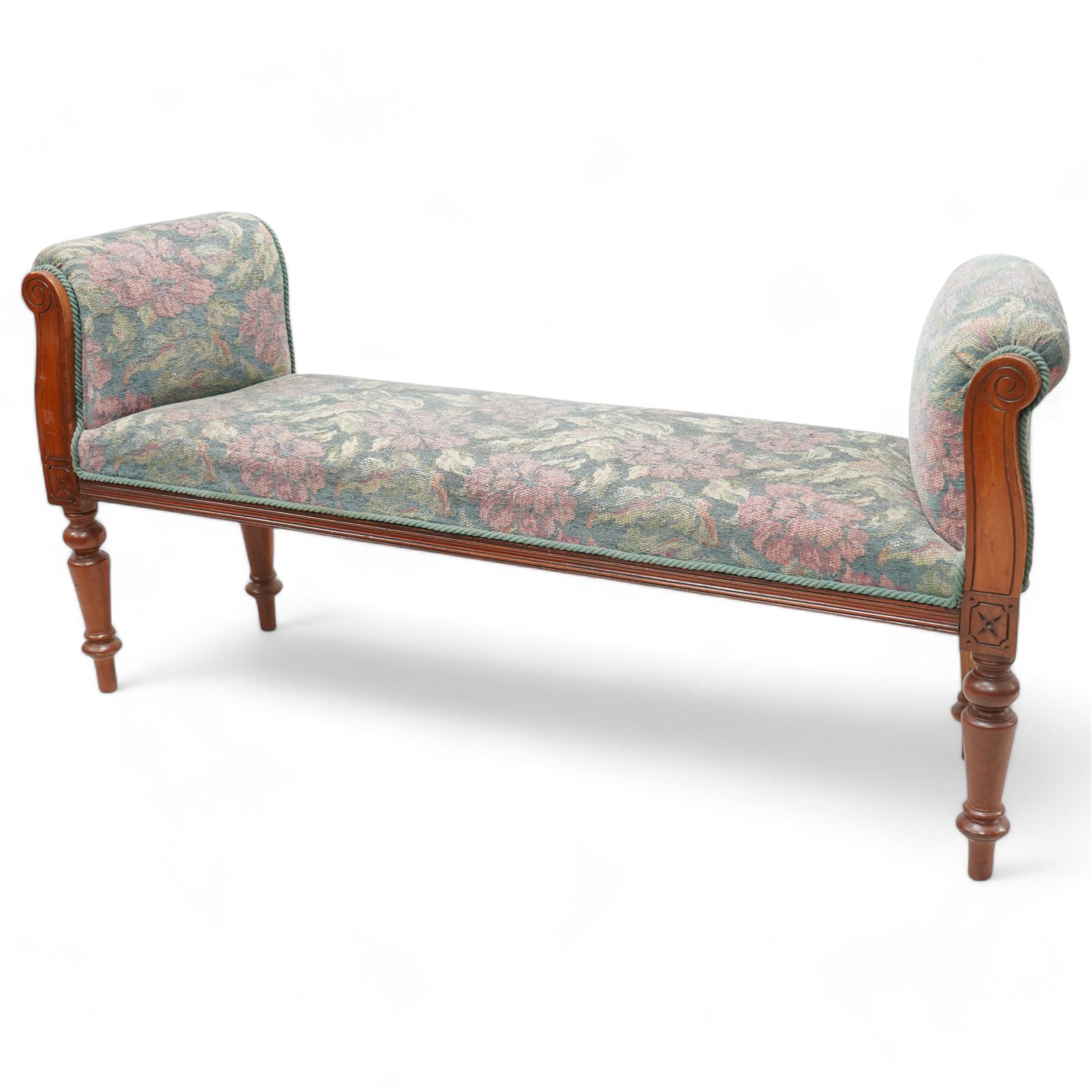 19th century mahogany framed bay window seat of tapered form, rolled arms decorated with carved scrolling, seat and arms upholstered in indigo ground floral patterned fabric, moulded lower rail over turned supports