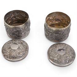 Pair of silver cylindrical dressing table boxes and covers embossed with trailing foliage H7cm, silver upright table photograph frame Birmingham 1909, Indian white metal and glass paperweight and a silver on copper trinket box