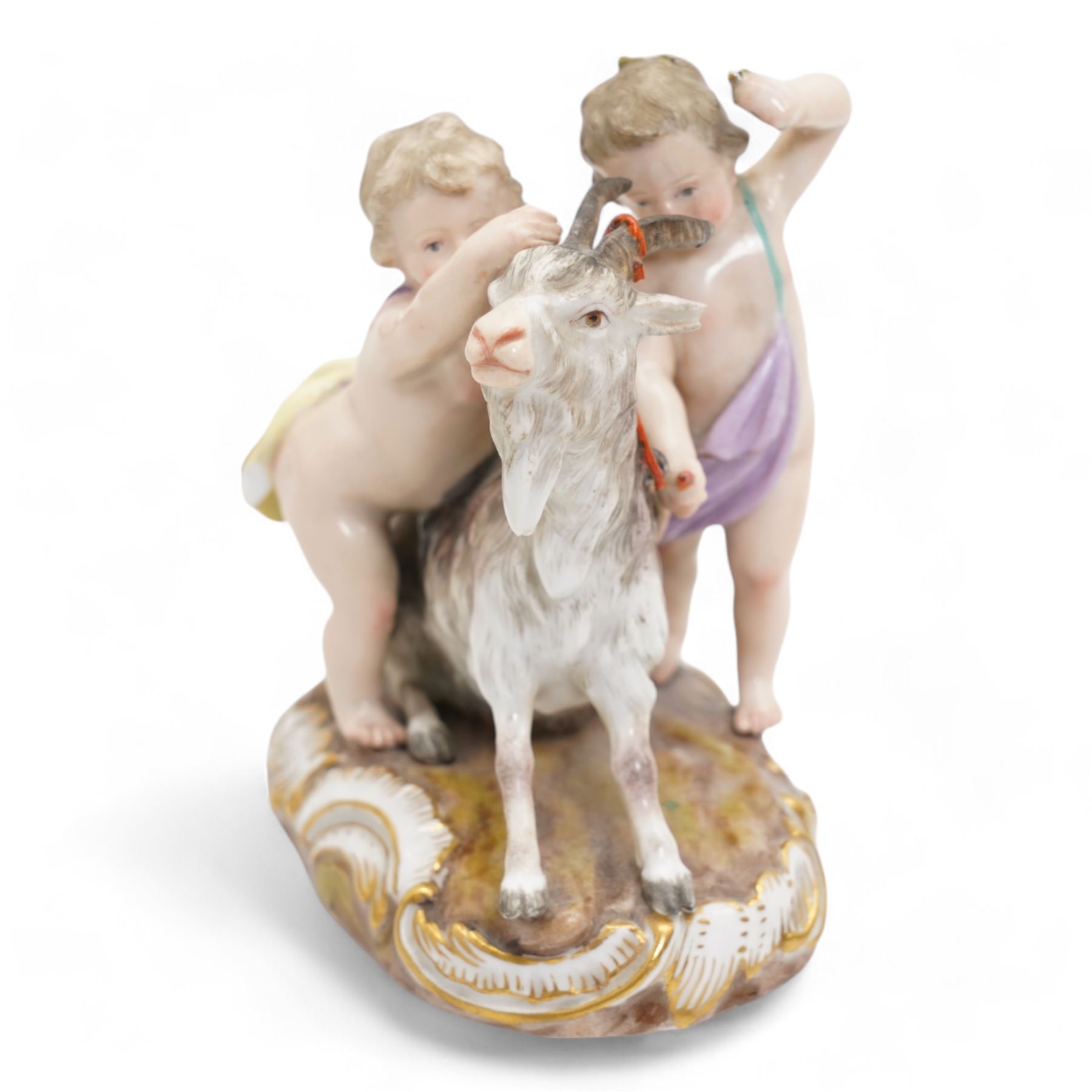 Meissen porcelain group modelled as two cherubs playing with a goat, the oval scroll moulded base heightened in gilt, blue crossed swords, inscribed no. 2454, H10cm, together with a Meissen figure of a young girl and boy, possibly emblematic of autumn, unmarked, (2) Provenance: From the Estate of the late Dowager Lady St Oswald