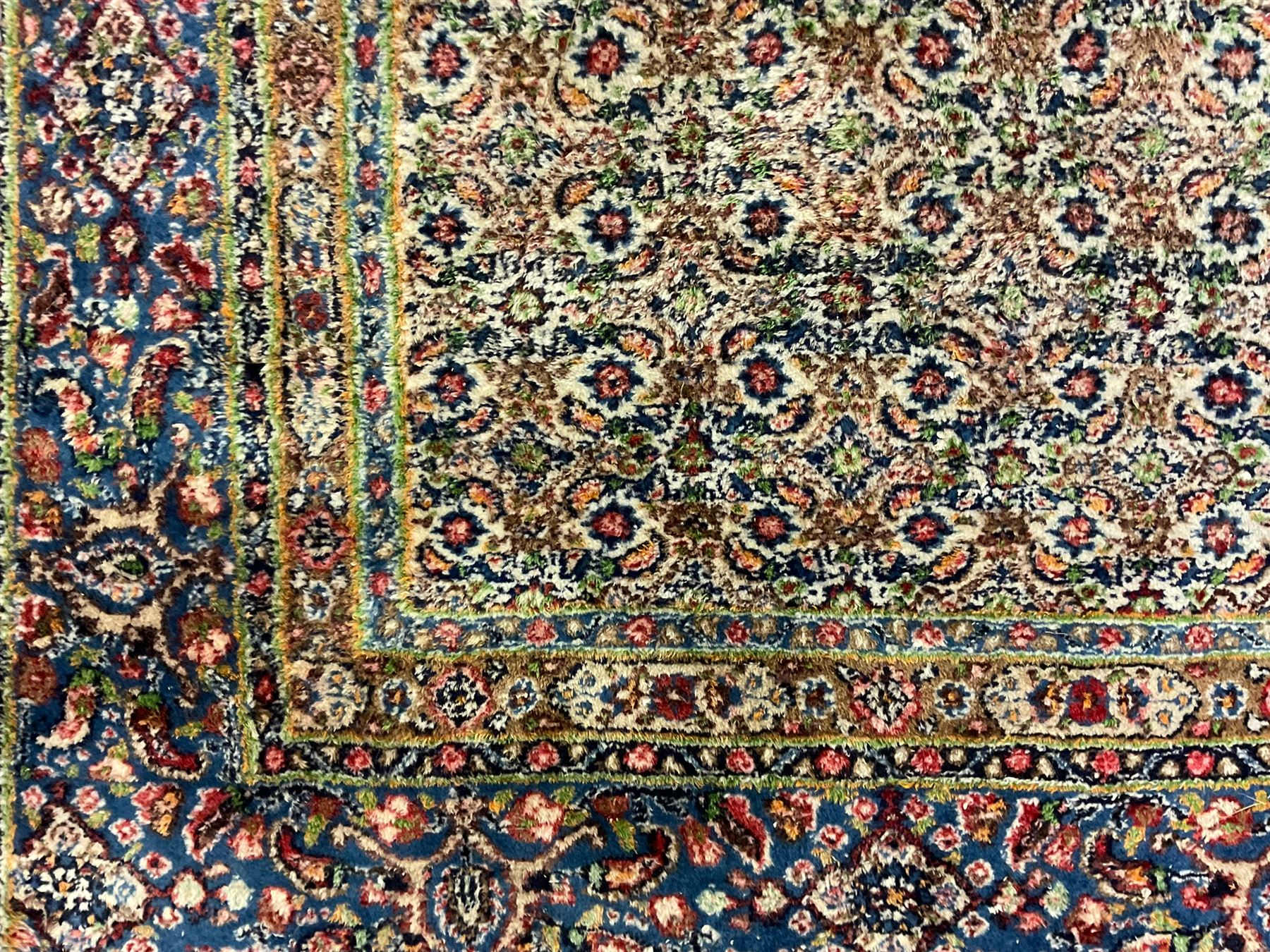 Persian indigo ground rug, the ivory field decorated with all-over flower heads, heavily guarded border with repeating stylised plant motifs