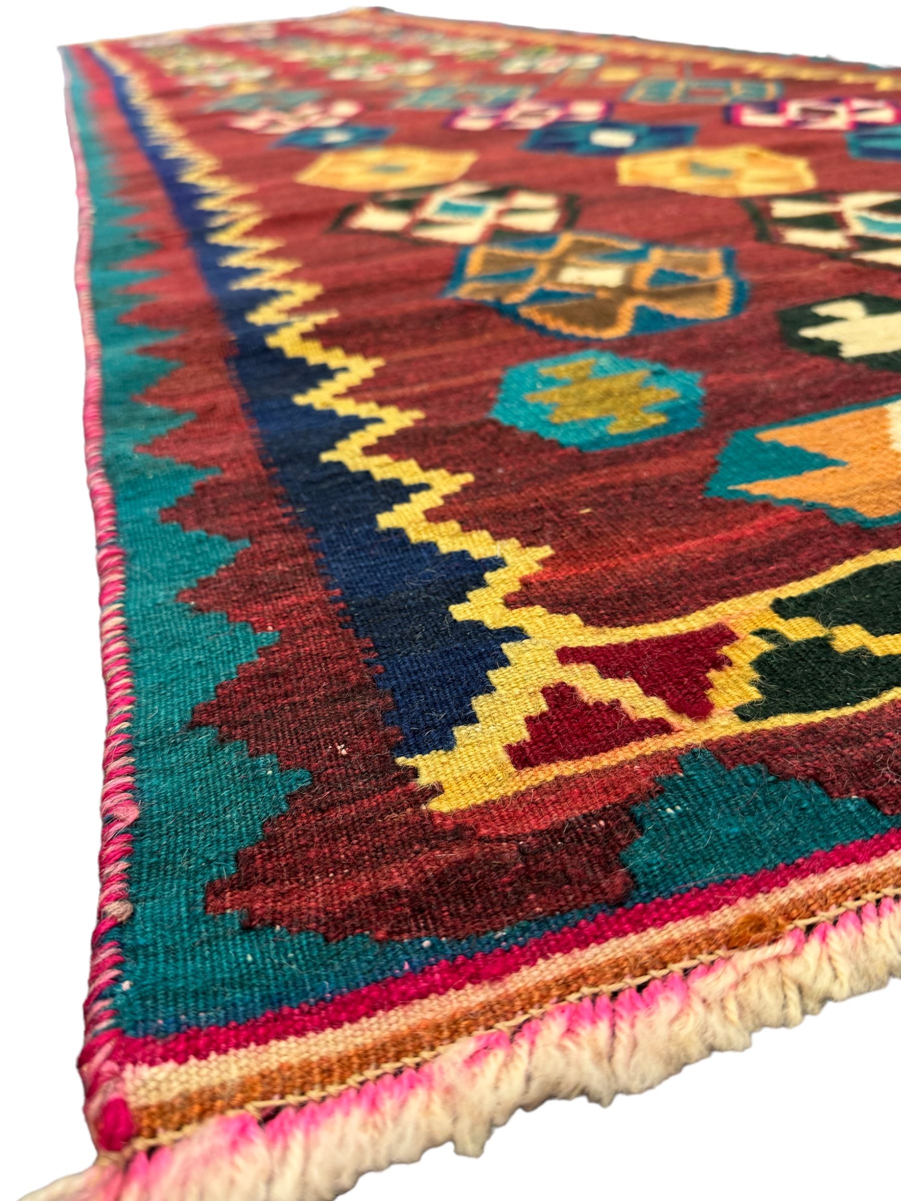 South West Persian Qashqai Kilim, crimson ground and decorated with three rows of geometric motifs, within zig-zag borders 