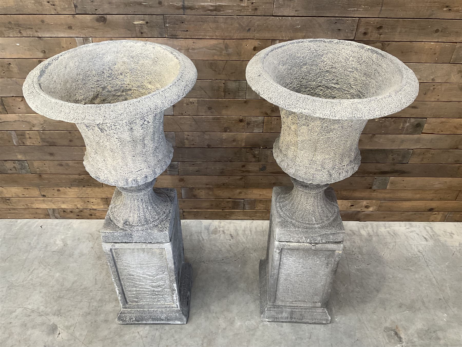 Pair of large Georgian design cast stone garden urns, egg and dart border, tapering column on square base, raised on square column