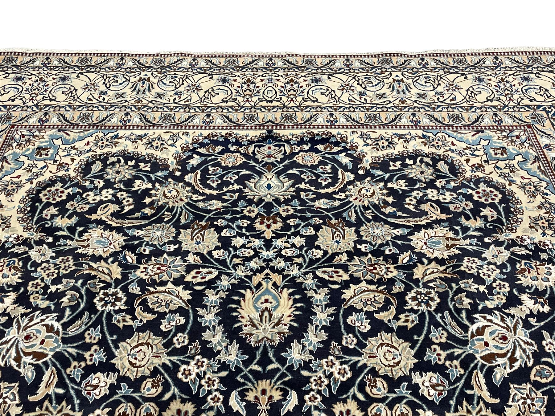 Persian Kashan indigo ground carpet, the central ivory rosette medallion surrounded by trailing and interlaced flower heads and branches, matching spandrels with floral design, the border with scrolling pattern decorated with stylised plant motifs within guards