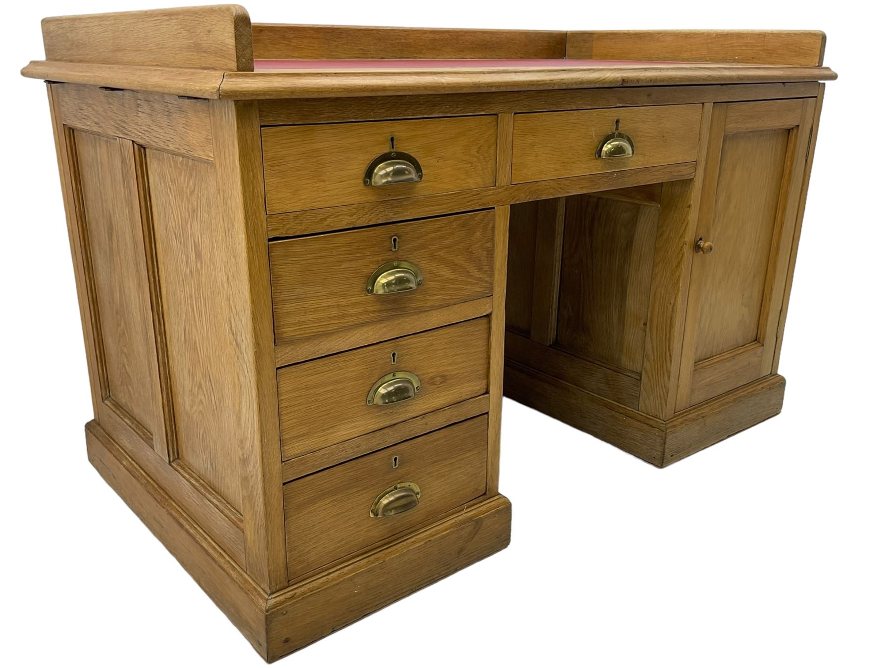 20th century oak desk, moulded rectangular top with raised back and inset leather writing surface, fitted with five drawers and single panelled cupboard, on moulded plinth base