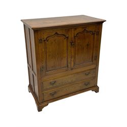 Oak drinks or media cabinet, projecting moulded cornice over two Gothic arch panelled doors on sliding tracks enclosing open storage, two drawers with brass drop handles, on bracket supports