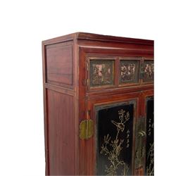 Late 19th century Chinese Qing dynasty red and black lacquered wood cabinet, Fujianese province, upper cupboard enclosed by two doors with relief carved and gilt panels depicting figures behind glass, the large cupboard enclosed by two panelled doors carved with trailing foliate branches and birds, inscribed with Chinese characters, to the left ‘Prolong life’ and to the right ‘Wealth and good fortune’, fitted with two drawers, square supports with carved brackets 