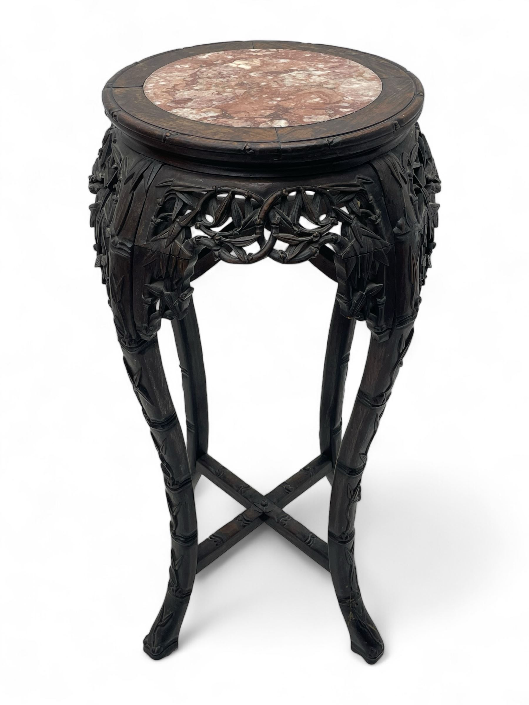 Early 20th century Chinese hardwood plant stand, circular top with marble inset, carved and pierced with interlacing foliage, on leaf carved supports united by x-framed stretchers