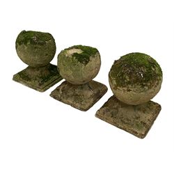 Set of three weathered cast stone gate post finials, circular orb on step-canted square base 