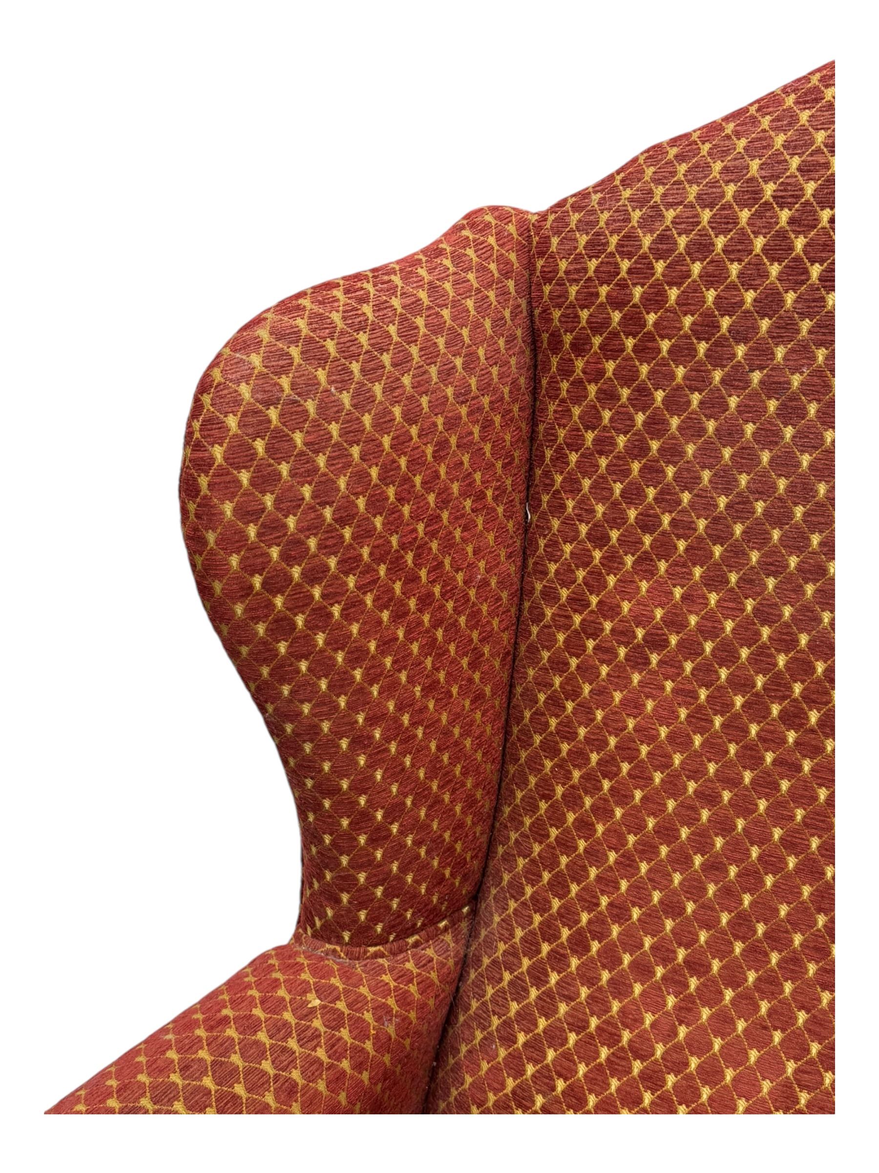 Early 20th century hardwood-framed wingback armchair, upholstered in red dotted fabric, on cabriole feet