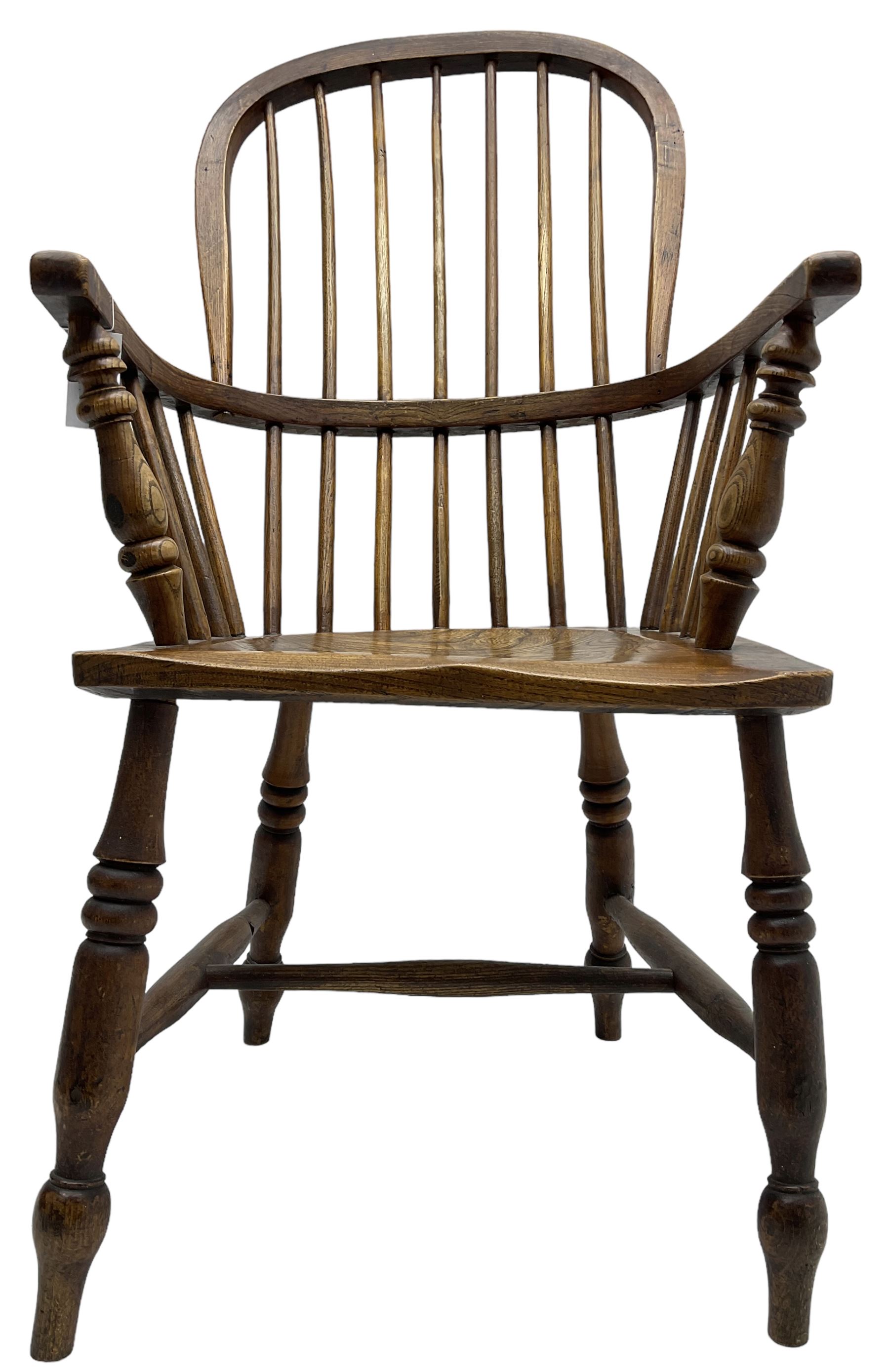 Early 19th century elm Windsor chair, high hoop and stick back over shaped saddle seat, raised on ring turned supports united by H-stretcher