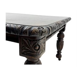 19th century heavily carved oak extending dining table, rectangular top with rounded corners and carved gadrooned edge, extending via winding mechanism with two additional leaves, raised on acanthus leaf-carved baluster supports terminating in ceramic castors