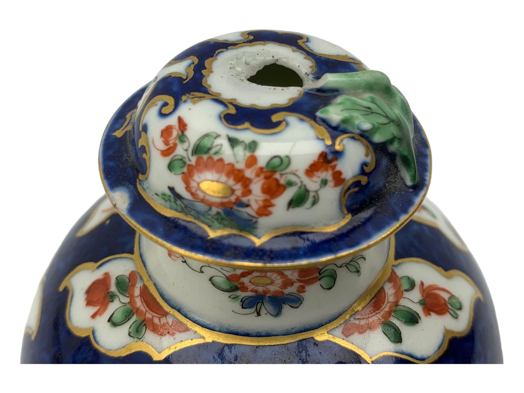 18th century Worcester tea caddy, of oval form and painted in the Kakiemon palette with reserves of flowers against a blue scale ground, H14cm together with a similar Worcester circular dish, painted with floral sprays, within a scalloped edge, blue crescent mark beneath, D19cm (2)