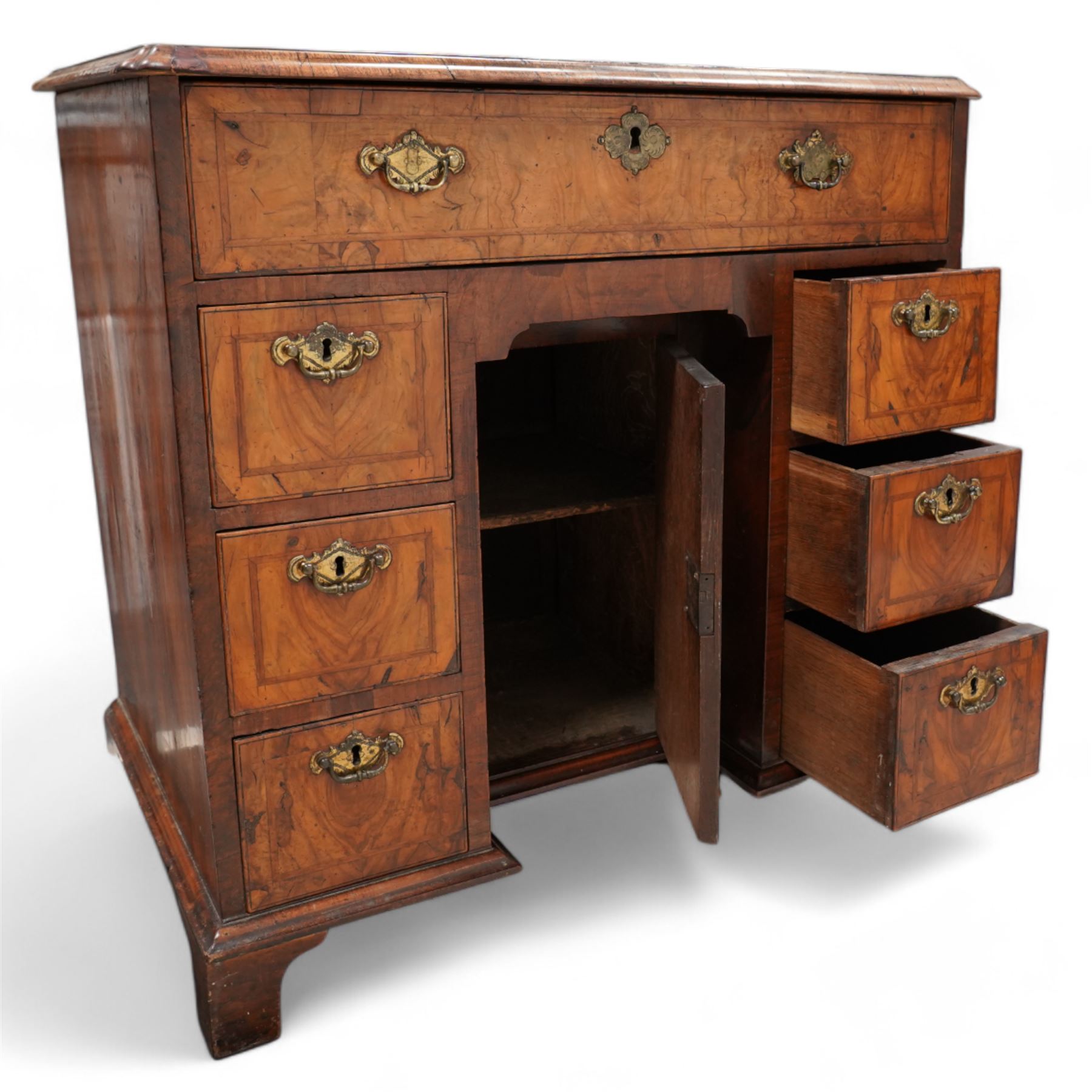 George II figured walnut knee-hole desk, the rectangular quarter-matched veneer top with moulded edge, crossbanding and feathered-banding, fitted with single frieze drawer over three drawers to each side, each with the central recess fitted with a single cupboard enclosing shelf, lower moulded edge on bracket feet