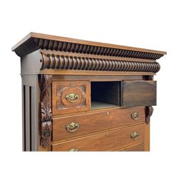 Late Victorian walnut Scotch chest, projecting cornice with turned quarter column mounts over matching half column to frieze, fitted with two upper short drawers with central cupboard, bevelled mirror glazed cupboard door, four graduating drawers below, foliage and flower head carved brackets to the uprights, panelled sides, chamfered plinth on turned feet