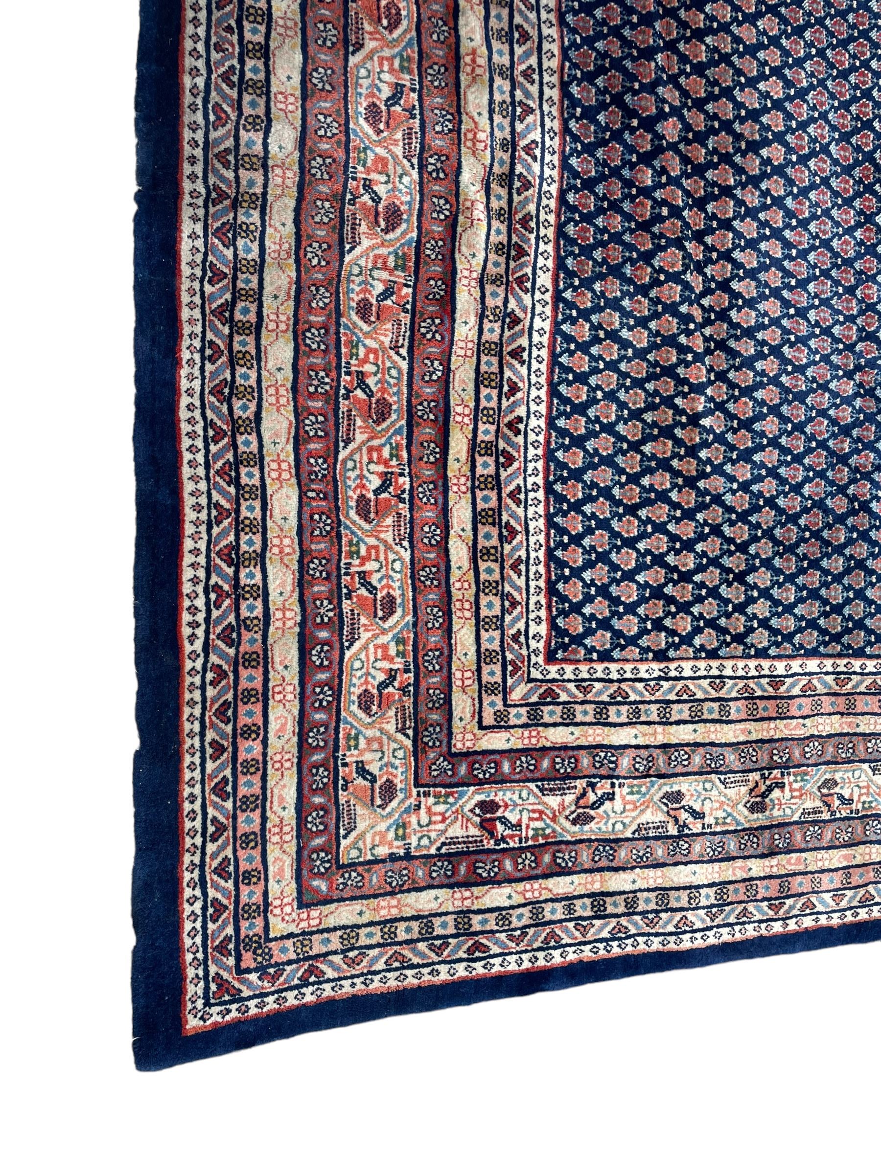 Large North-West Persian Arrak indigo ground carpet, the field decorated all-over with small Boteh motifs, multiple band border decorated with repeating geometric designs