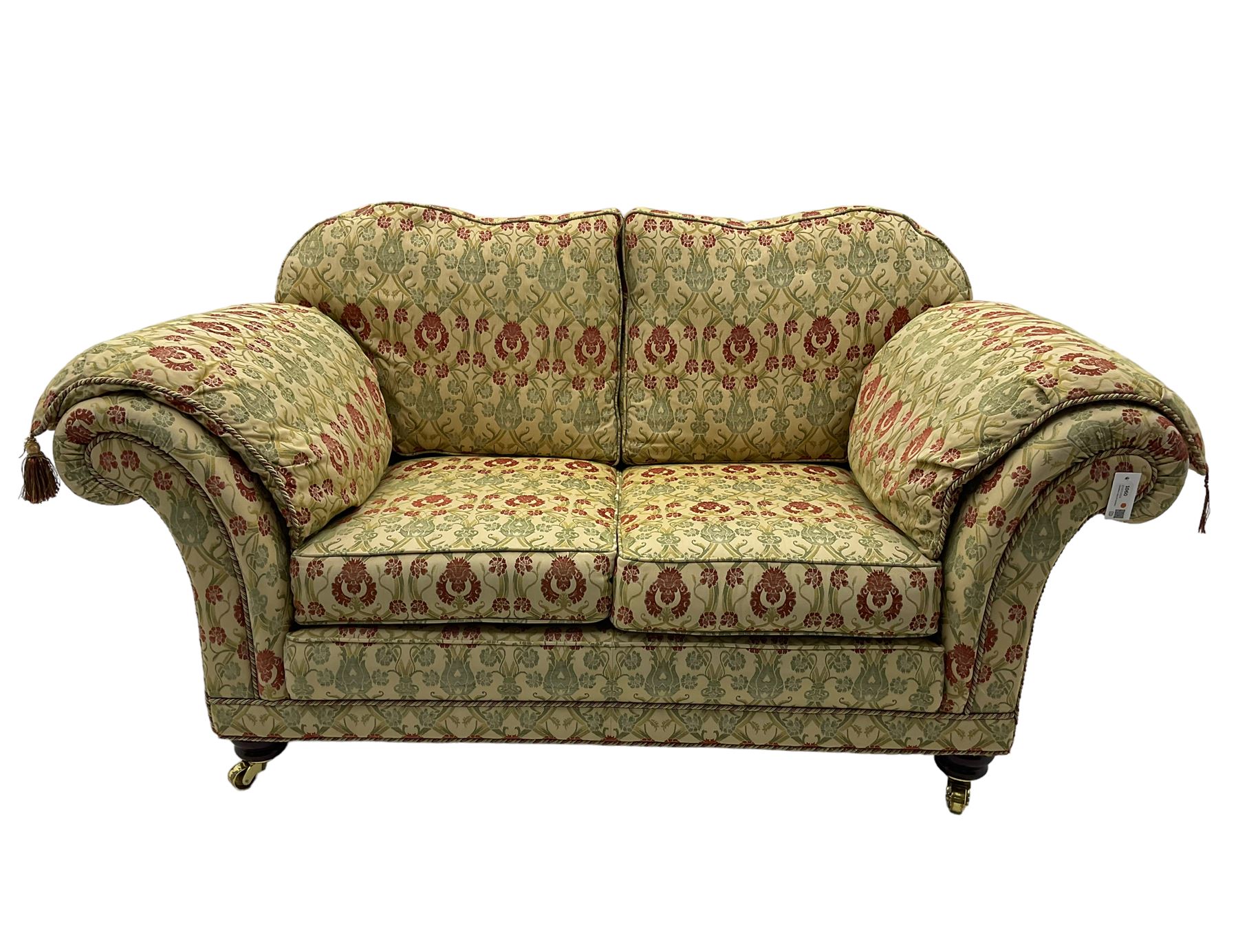 Traditional design two seat sofa, high back with scrolled arms, upholstered in beige fabric with red and green damask motifs, on castor supports (L178cm, D100cm, H89cm); matching armchair (L109cm, D89cm, H89cm)