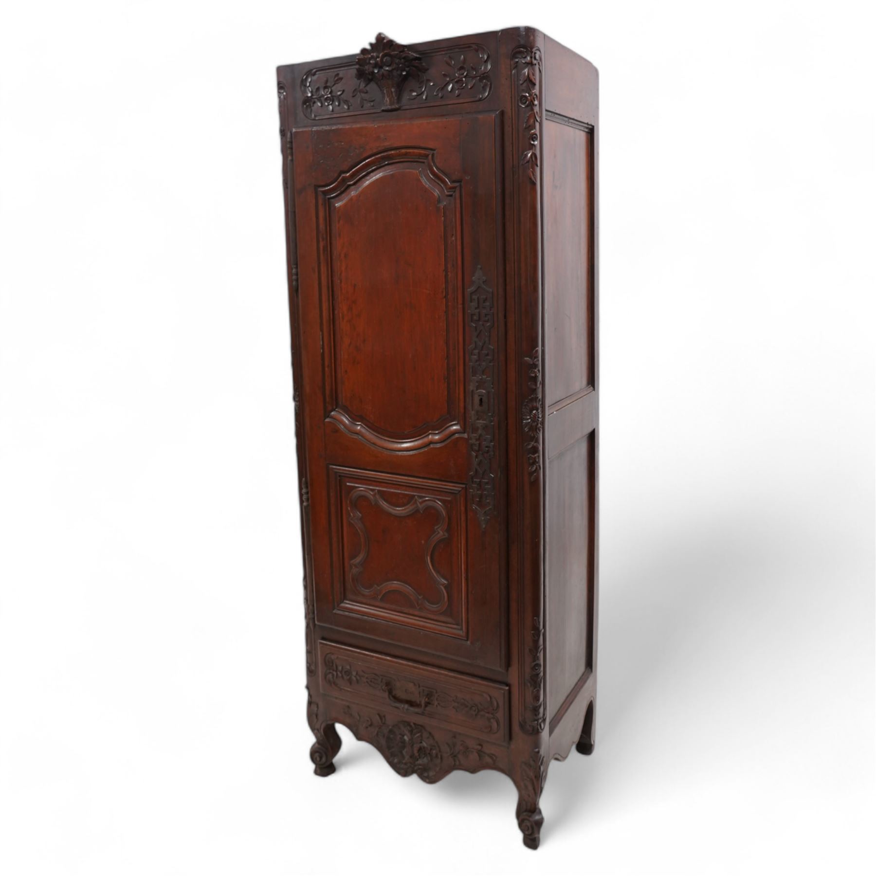 19th century French walnut hall cupboard, the frieze carved with a bouquet of flowers and trailing foliate decoration, enclosed by single panelled door over single drawer, the curved outer corners decorated with trailing leafy branches and flower heads, shaped apron with scroll carved cabriole feet 