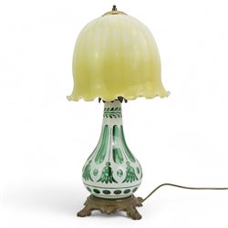 Early 20th century Bohemian green and white glass overlaid table lamp, of bulbous form with tapering neck, decorated with flower heads, with associated butterscotch mushroom form glass shade with wavy rim, on a cast brass base with four lion paw supports, H53cm