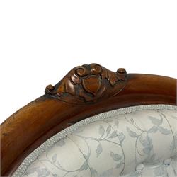 Victorian walnut nursing chair, the curved cresting rail carved with central cartouche and scroll leaves, upholstered in pale blue fabric decorated with trailing floral design, on cabriole front feet 