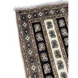 Persian ivory ground rug, the field divided into stripes decorated with stylised flower heads, the border with repeating cross motifs within guard stripes 