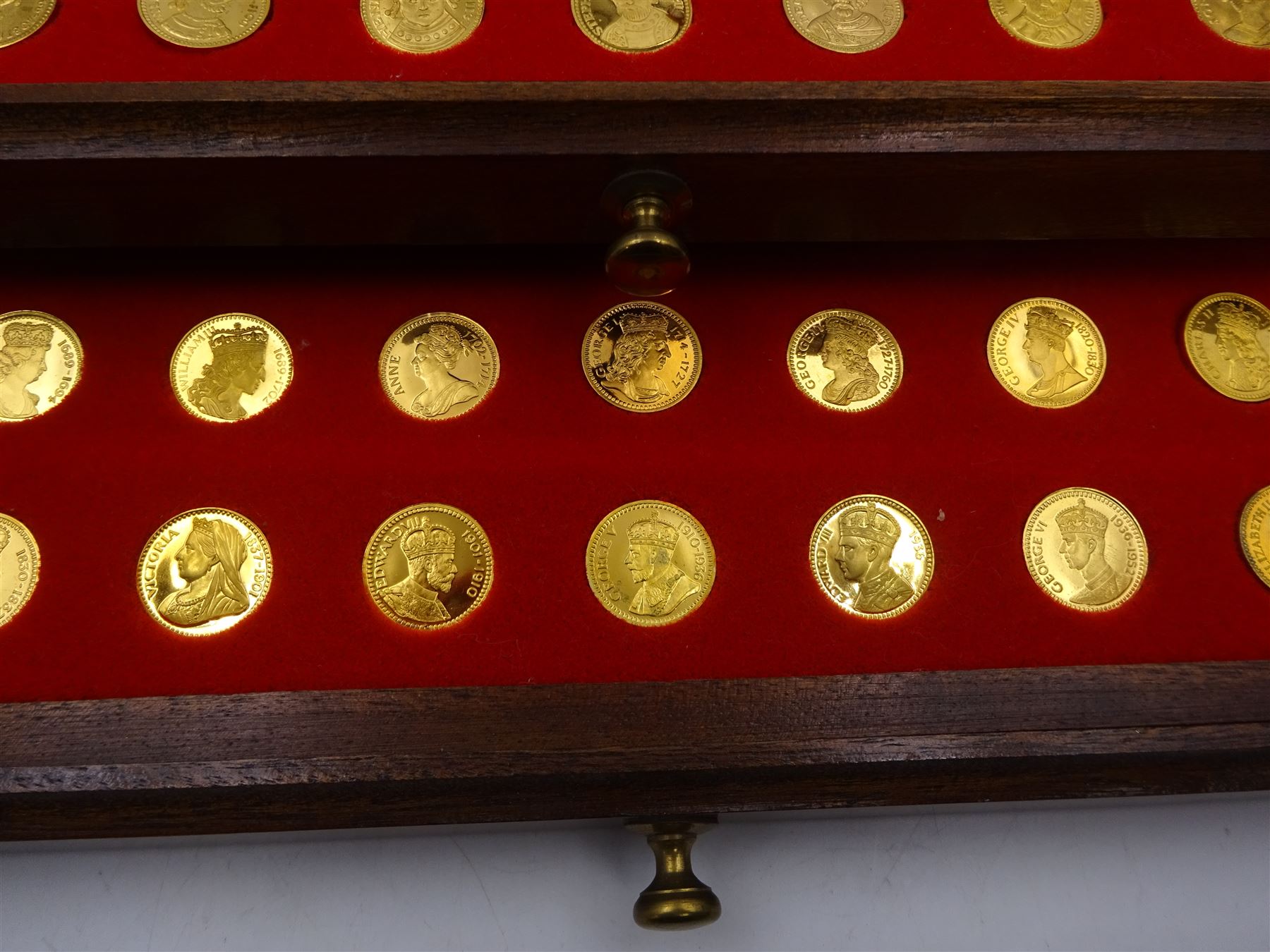 Danbury Mint, Our Royal Sovereigns Collection, seventy 22 carat gold plated silver medallions depicting the complete line of British monarchs to mark the 1200th anniversary of the first coronation, contained within wooden table top collectors cabinet with two drawers, with certificate of authenticity, with two drawers, hallmarked Danbury Mint, London various dates