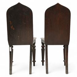 Pair of 19th century carved oak hall chairs, the arched back carved with moulded scalloped decoration with a central applied shield motif, canted panelled seat over turned octagonal supports