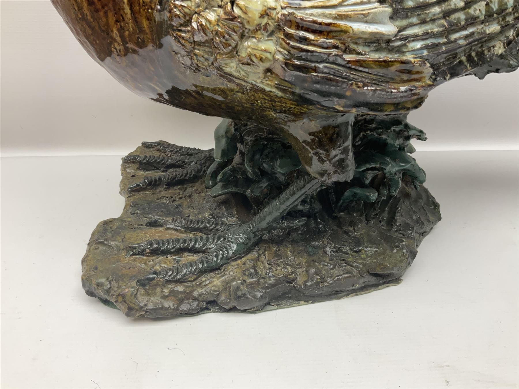 Large stoneware sculpture modeled as a Ring Neck Pheasant, upon a naturalistic base, H55cm, L78cm