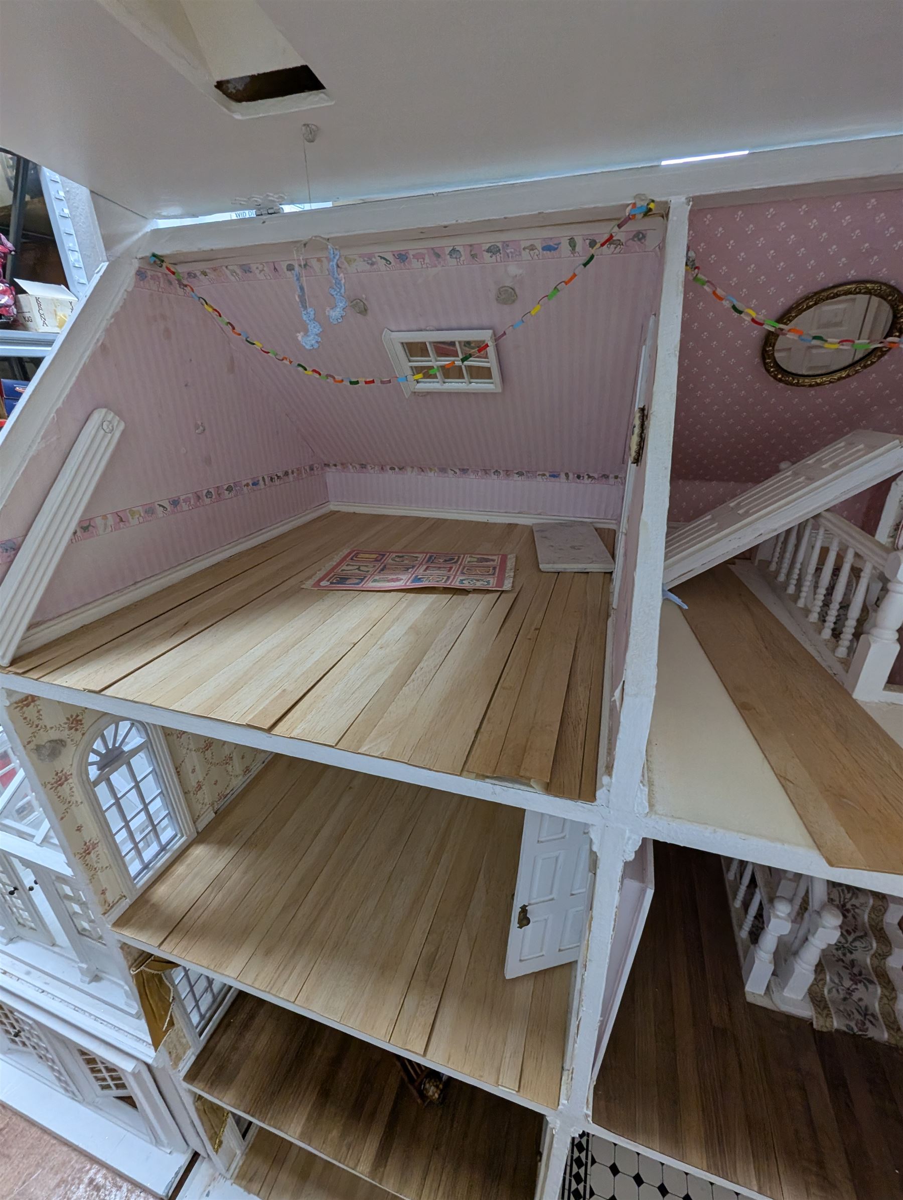 Large three storey modern dolls house, painted white with latticed windows, grey roof and metal fencing, with decorated interior, together with two dolls house garden rooms and two conservatories