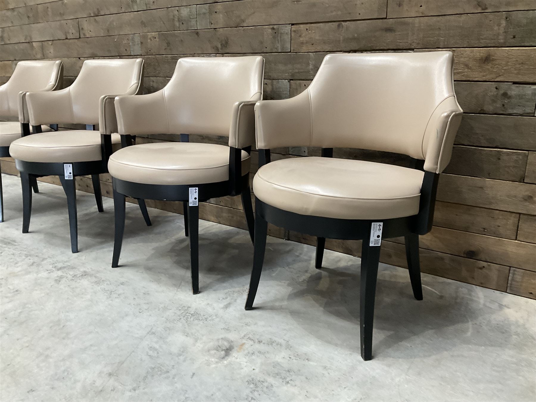 Four ebonised framed tub shaped armchairs, upholstered in beige fabric