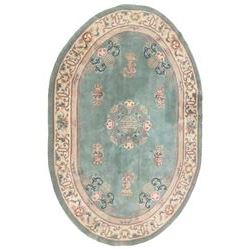 Chinese pale turquoise ground washed woolen rug, oval form decorated with bouquets of floral designs and Chinese characters, enclosed by a wide guard band