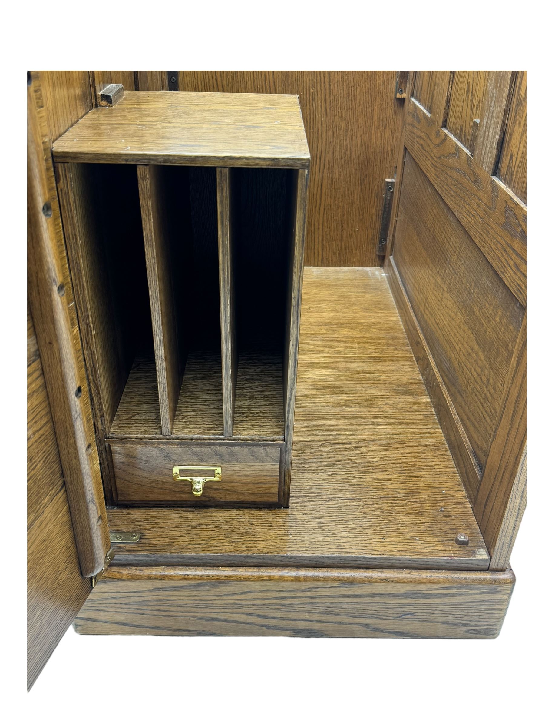 Early 20th century oak tambour roll-top desk, the top with fitted interior including drawers, pigeonholes and compartments, the twin pedestals fitted with four drawers with carved handles, supported by plinth base 