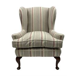 Georgian design hardwood-framed wingback armchair, curved wingback terminating to curved and rolled arms, upholstered in striped fabric with loose seat cushion, on cabriole front feet 