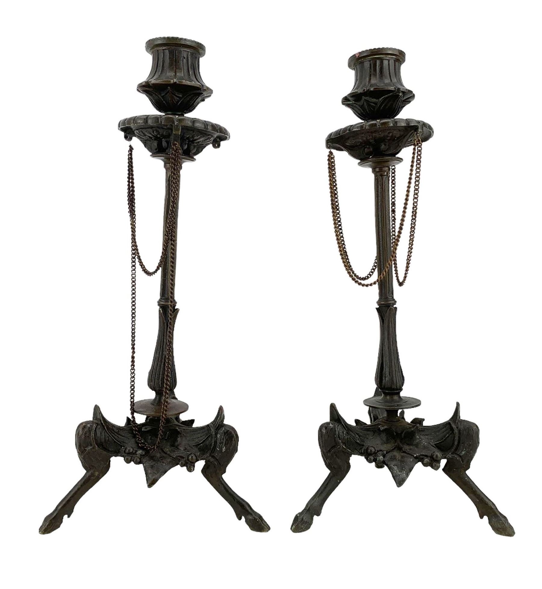 Pair of 19th century French patinated bronze candlesticks in the manner of Ferdinand Barbedienne, the gadrooned sconces hung with chains, reeded columns on tripod supports with hoof feet, H28cm 