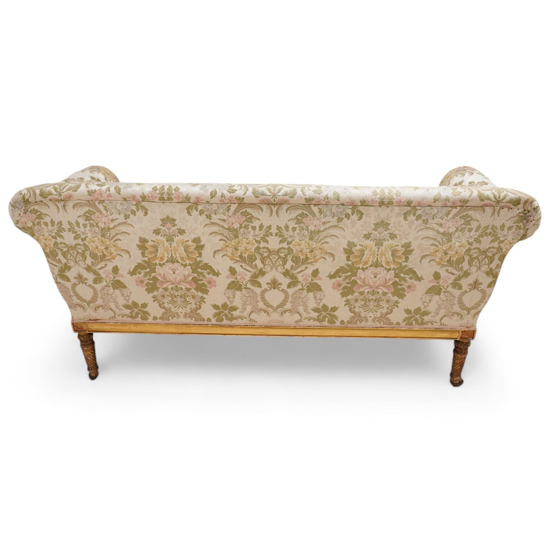 19th century gilt wood and gesso settee, upholstered in repeating floral pattern fabric, rolled arms decorated with trailing bead moulding and acanthus leaf, the seat rail with flower head band, on twist turned and foliate carved feet with brass castors 