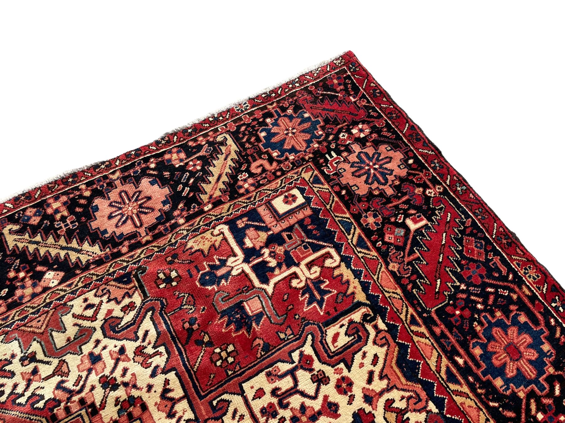 Persian Heriz red ground carpet, large central eight point medallion with projecting palmettes surrounded by small geometric motifs, decorated profusely with hooks, rosettes and animals, the busy border decorated with stylised foliate motifs within guard stripes 