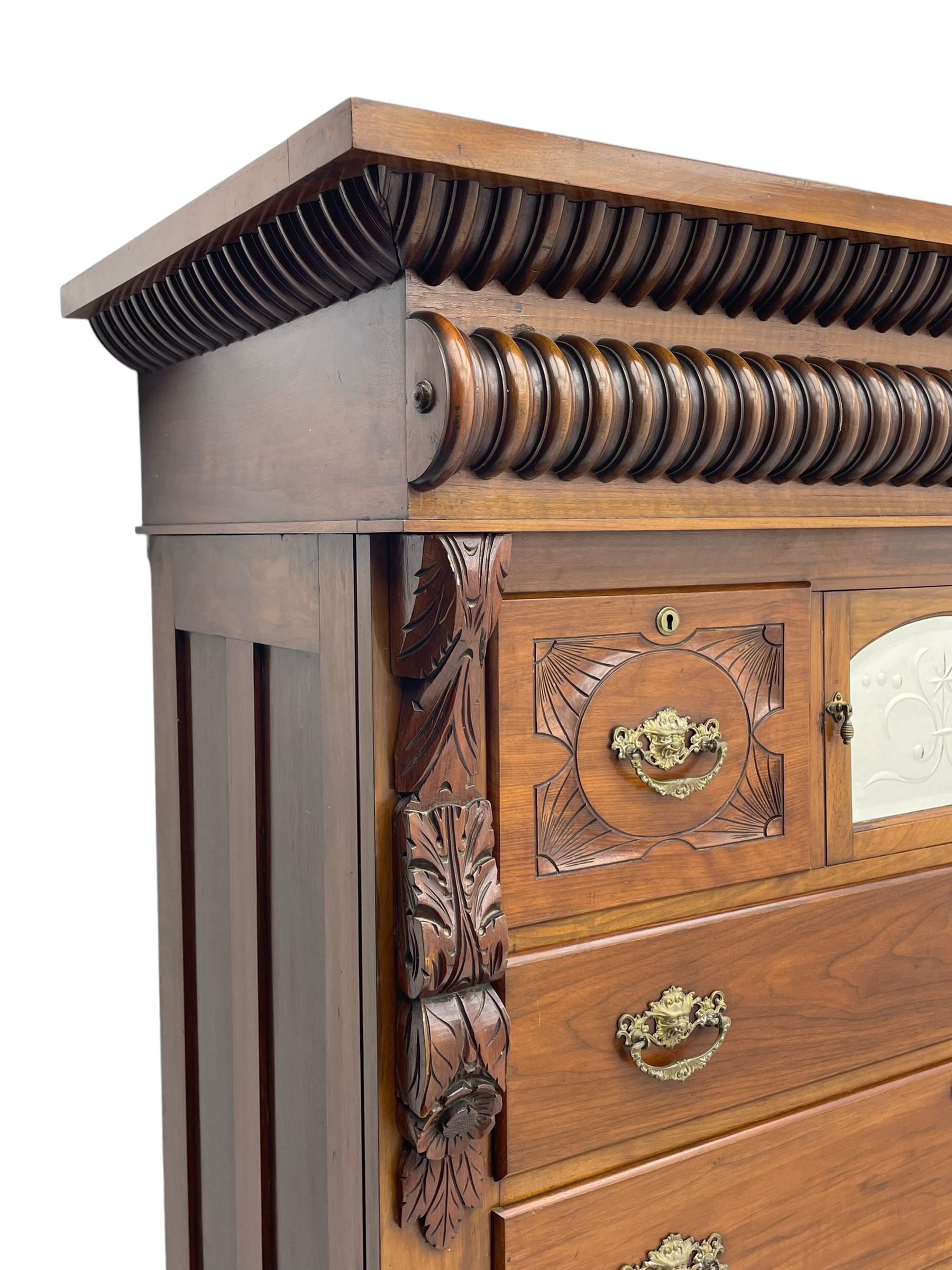 Late Victorian walnut Scotch chest, projecting cornice with turned quarter column mounts over matching half column to frieze, fitted with two upper short drawers with central cupboard, bevelled mirror glazed cupboard door, four graduating drawers below, foliage and flower head carved brackets to the uprights, panelled sides, chamfered plinth on turned feet