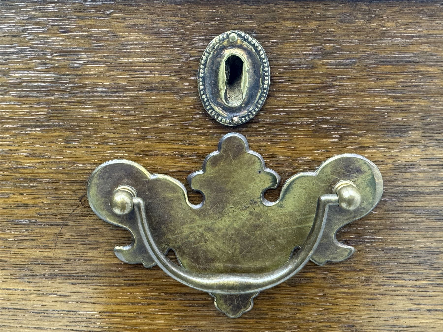 George III oak chest, rectangular top with moulded edge over two short and three long graduated drawers, each with brass escutcheons and shaped backplate handles, on turned bun supports 