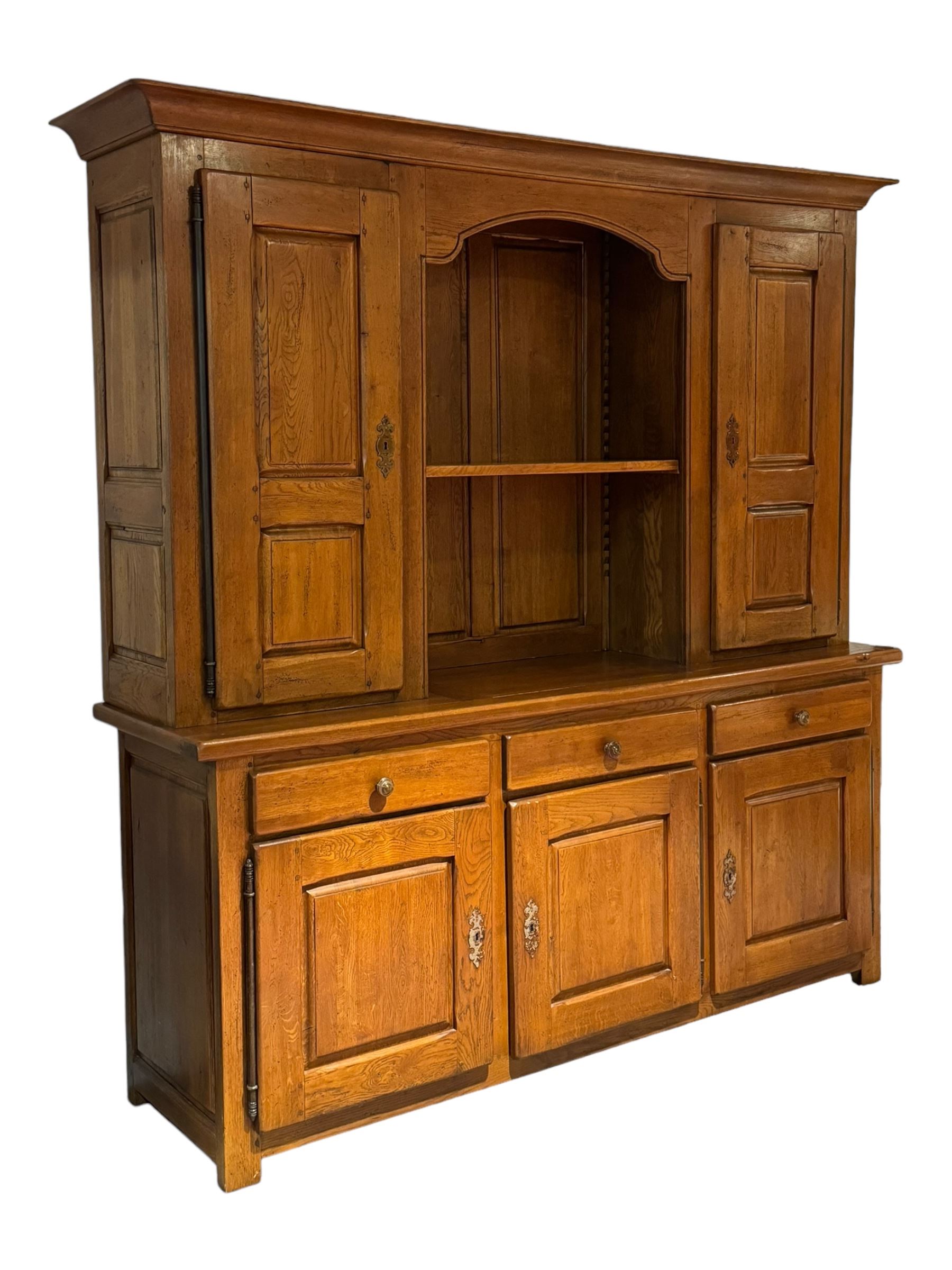 Large 20th century oak dresser, projecting cornice over open arched central section with two shelves, flanked by two panelled cupboards with two shelves, lower section with three drawers above three cupboards, on stile supports 