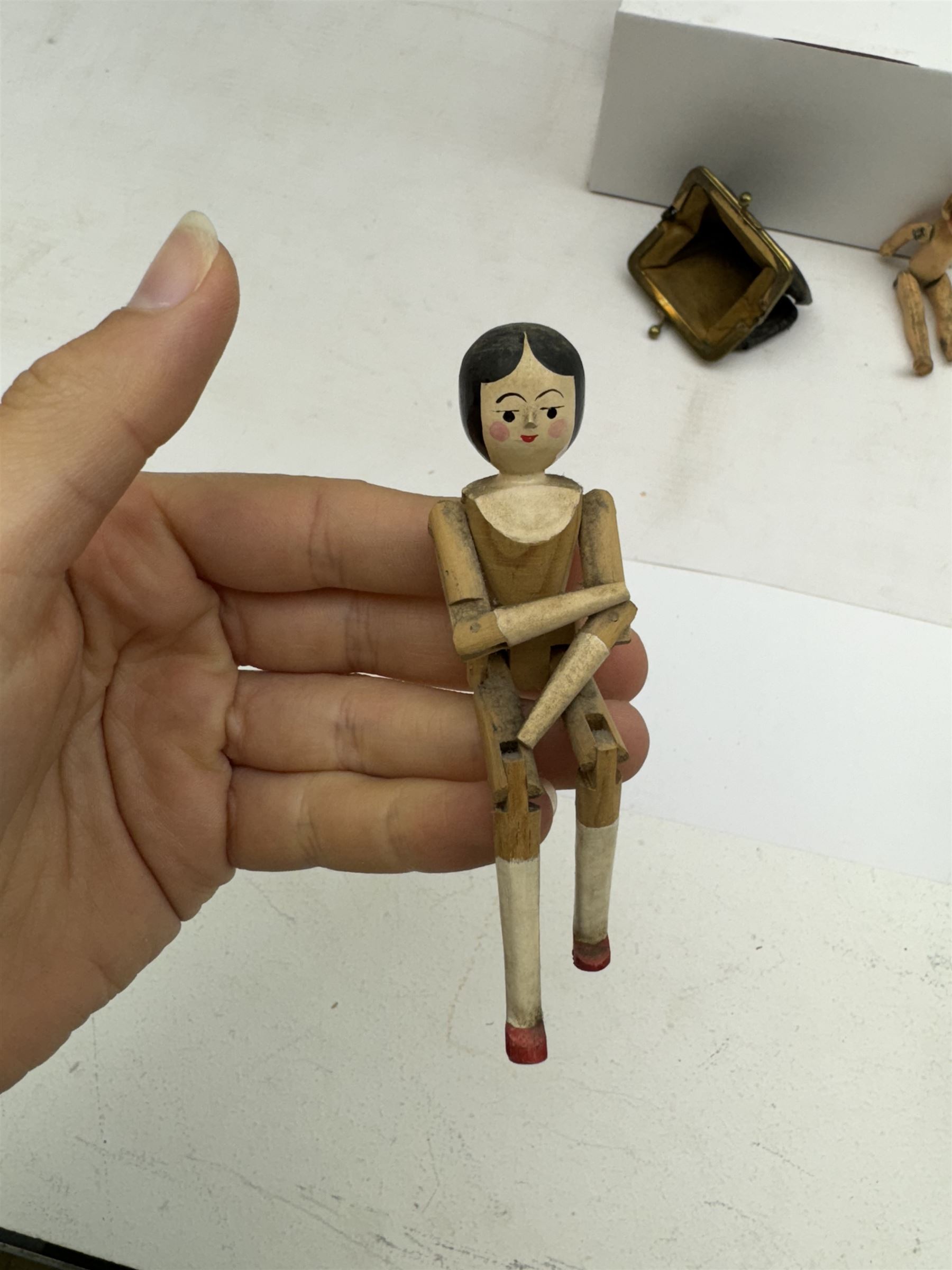 Four miniature dolls with articulated limbs, and a miniature purse