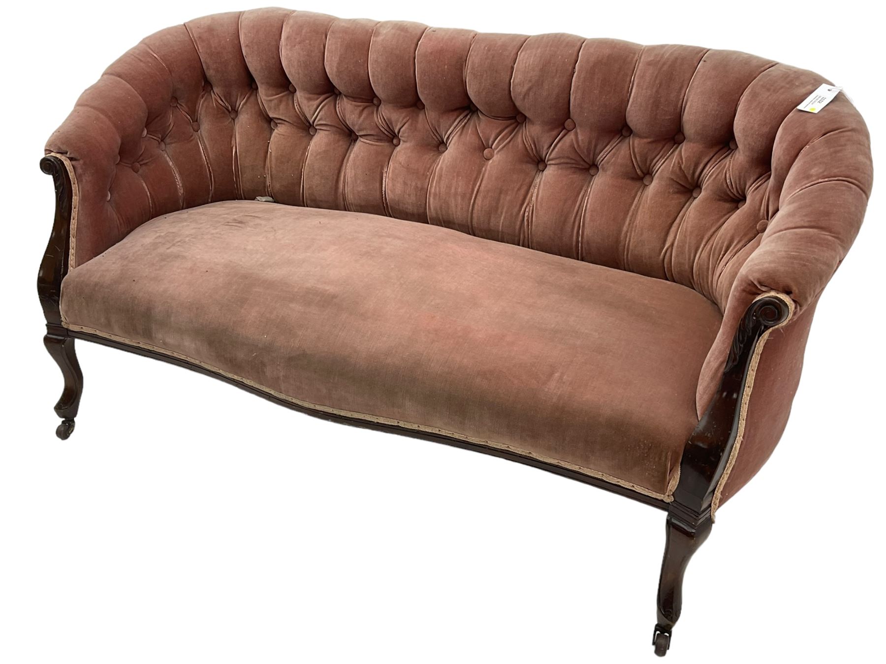 Late 19th century mahogany framed two-seat sofa, upholstered in buttoned pink fabric, on cabriole front supports, on castors 