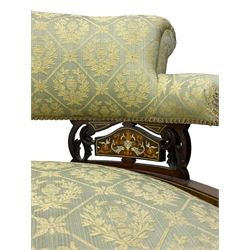 Late Victorian walnut salon settee or chaise lounge, double-ended with rolled back and curved end, upholstered in light aquamarine fabric with raised repeating lozenge pattern, decorated with laurel leaf wreaths and urns, three pierced splats carved with curled leaves, inlaid with dolphins and scrolled foliate motifs in simulated ivory and boxwood, on tapering ring turned supports with brass and ceramic castors (L166, D60, H70cm); together with matching tub-shaped armchair (W61cm, H73cm, D66cm)  