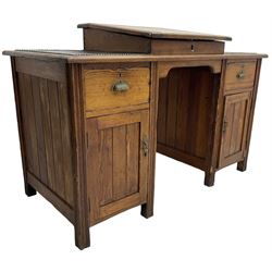 Edwardian pitch pine desk, rectangular top with writing slope flanked by inset leather writing surfaces, over twin pedestals each with shell cup handled drawer over cupboard, the left enclosing two shelves, the right enclosing sliding trays, on fluted straight supports