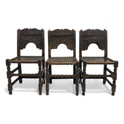 Set of three 18th century carved oak back stools, the cresting rail carved with scrolling foliate motifs over an arched panel with a stylised tree carving with extending leafage, the panelled seat held within a bobbin-turned frame, raised on turned supports united by a ring-turned front stretcher