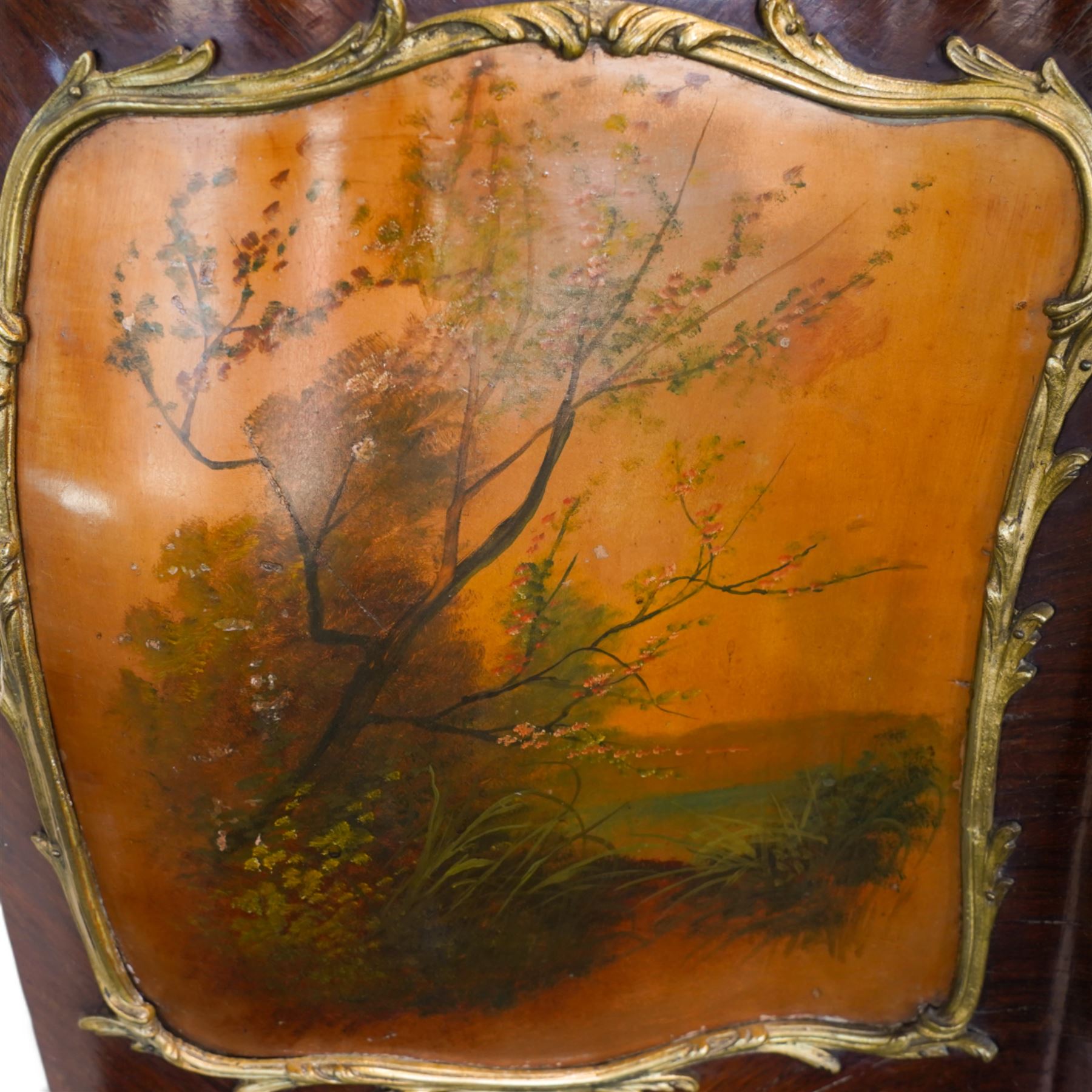 Large early 20th century French gilt metal mounted vitrine, serpentine and bombe form, C-scroll pediment decorated with extending flower heads, shaped front enclosed by single glazed door and glazed with shaped glass panes with foliate cast edging, floral pattern silk lined interior fitted with two glass shelves and one lined shelf, hand painted with Vernis Martin design panels depicting garden courting scene and putti, on cabriole supports mounted by shell and C-scroll mounts 