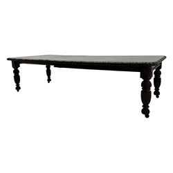 19th century heavily carved oak extending dining table, rectangular top with rounded corners and carved gadrooned edge, extending via winding mechanism with two additional leaves, raised on acanthus leaf-carved baluster supports terminating in ceramic castors